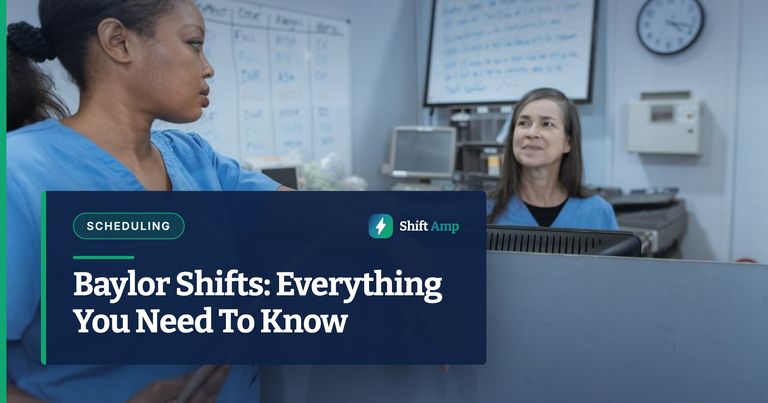 Nurses in scrub suits discussing medical tasks in a clinical environment.
